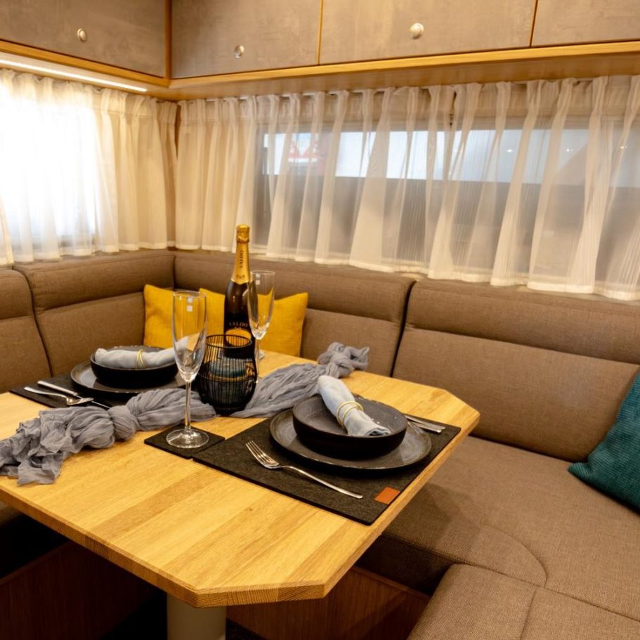 Erleben Gemütlicher Wohnbereich mit Tisch, Geschirr, Champagner und hellem Dekor.