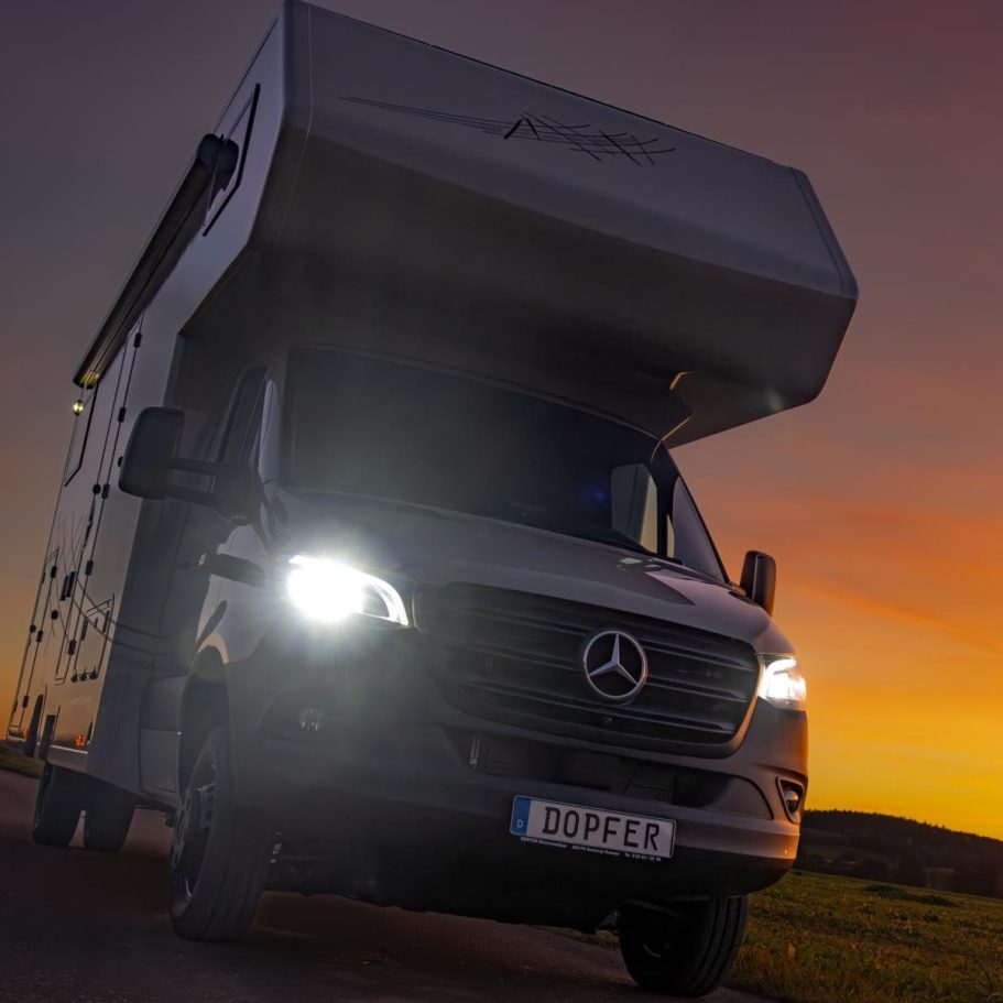 Abenteuer Ein Wohnmobil bei Sonnenuntergang, mit eingeschaltetem Scheinwerfer.